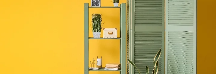 Grüner Raumteiler und grünes Regal vor gelber Wand